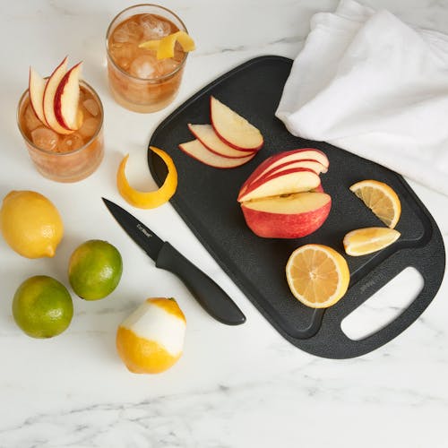 Apple and Lemon on the cutting board with a paring knife on a kitchen counter.