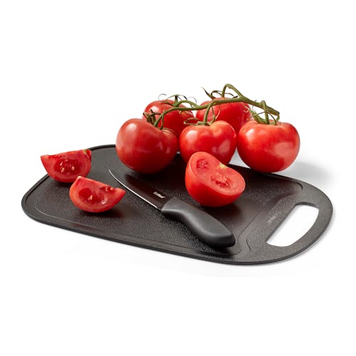 Tomatoes and a knife on the cutting board for the EatNeat 18-piece knife set.