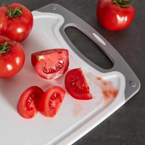 Sliced tomato on the cutting board with juice being trapped in the juice grooves.
