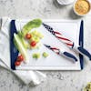 2 American flag knives on the cutting board along with lettuce and tomatoes.
