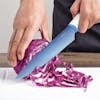 Light blue chef's knife being used to cut an onion.
