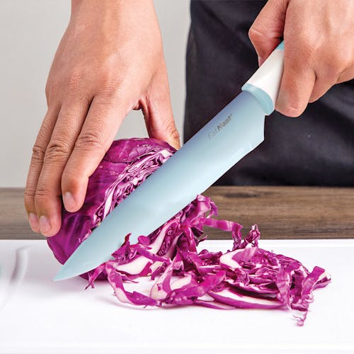 Light blue chef's knife being used to cut an onion.