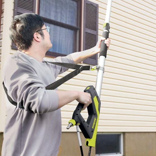 Man using the Sun Joe 18-Foot Pressure Washer Sky Lance to clean the side of a house.