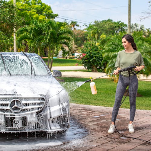 Woman using the Sun Joe 34-ounce Foam Cannon for SPX Series Electric Pressure Washers to clean a Mercedes car.