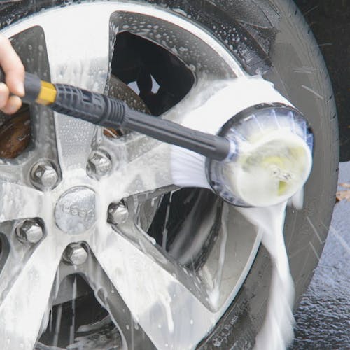 Sun Joe Rotary Wash Brush Kit Attachment for pressure washers washing the rim of a car tire.