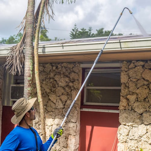 Man using the gutter cleaning attachment for SPX series pressure washers to clean the gutters of a house.