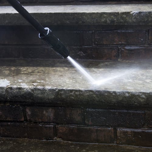 Spray wand being used to clean dirt off of cement steps.