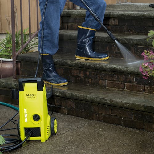Person using the Sun Joe 11-amp Electric Pressure Washer with 1450 PSI to clean steps.