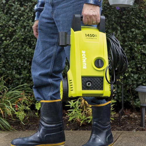Person holding the Sun Joe 11-amp Electric Pressure Washer with 1450 PSI from the handle.