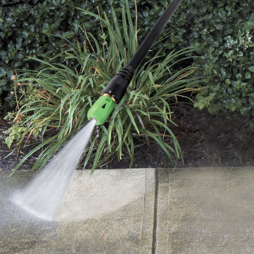 Spray wand with a quick-connect nozzle attached cleaning a sidewalk.