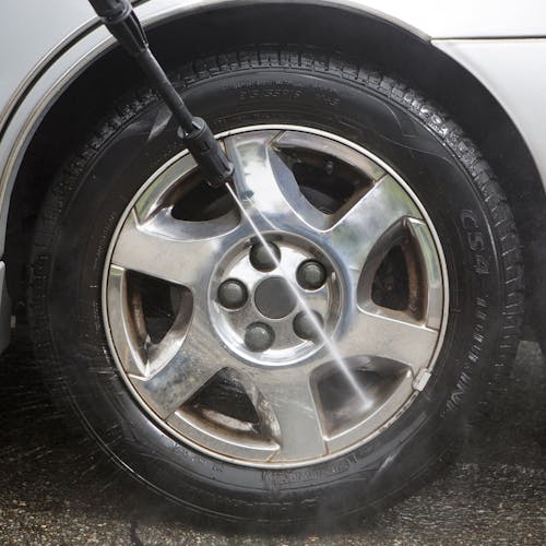 Spray wand being used to clean a car tire.
