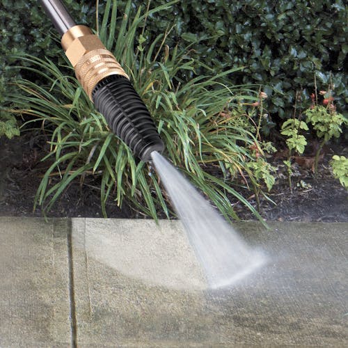 Spray wand being used to clean dirt off of pavement.