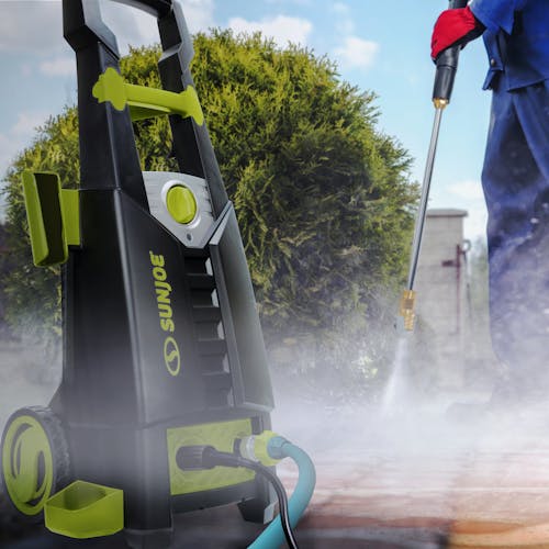 Sun Joe 13-amp 2000 PSI Electric Pressure Washer being used to clean a driveway.
