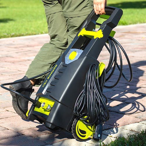 Sun Joe 13-amp 2000 PSI Electric Pressure Washer being wheeled across a driveway.