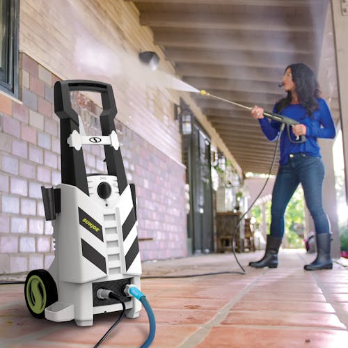 Woman using SPX2970-MAX electric pressure washer to clean siding