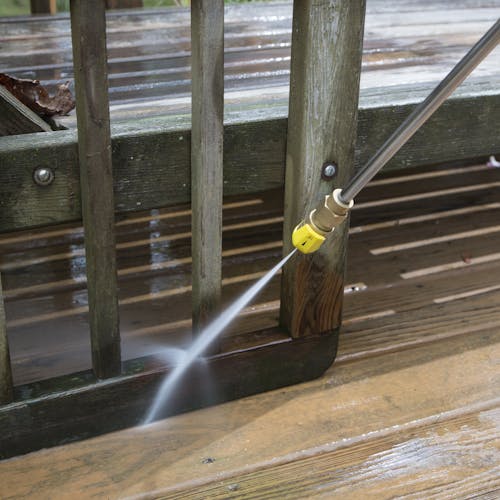 Spray wand being used to clean a wooden deck.
