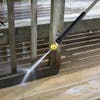 Spray wand being used to clean a patio deck.