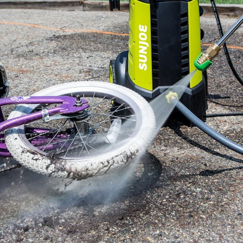 Sun Joe 14.5-amp 2030 PSI Electric Pressure Washer being used to clean the tire of a bike.