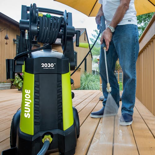 Sun Joe 14.5-amp 2030 PSI Electric Pressure Washer being used to clean a wooden patio deck.