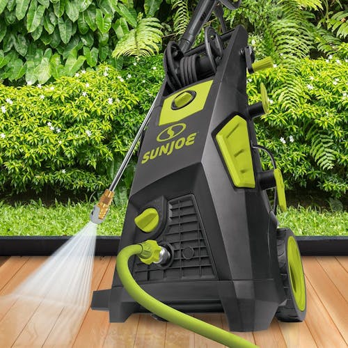Sun Joe 13-amp 2250 PSI Brushless Induction Electric Pressure Washer on a deck with the spray wand cleaning the wood.