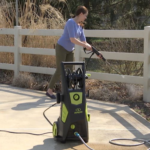 Sun Joe 13-amp 2250 PSI Brushless Induction Electric Pressure Washer being used to clean a white fence.