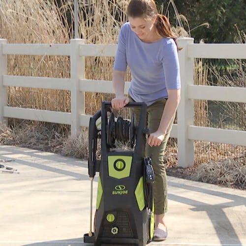 Woman reeling in the hose on the Sun Joe 13-amp 2300 PSI Brushless Induction Electric Pressure Washer.