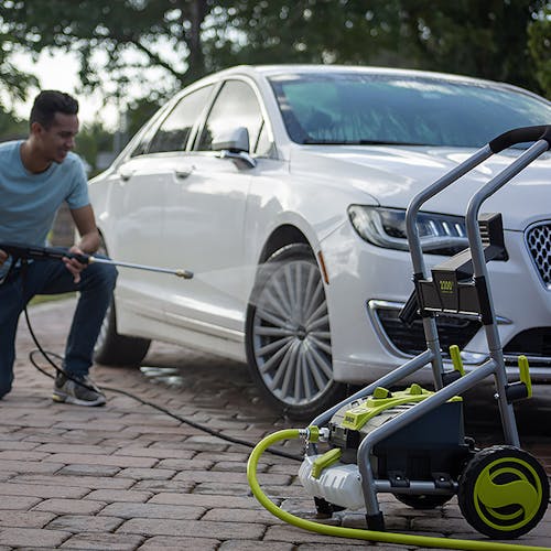 Man using the 14.5-amp electric pressure washer to clean the rims and wheels on his car.