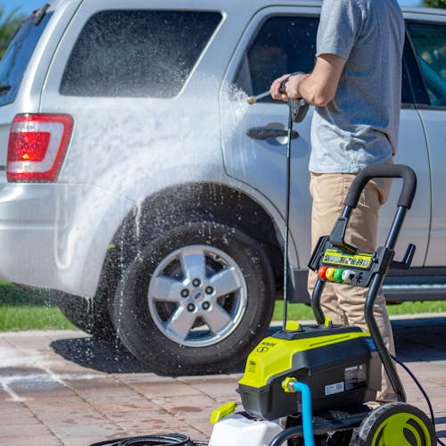 Sun Joe pressure washer detergent being used to wash a car.