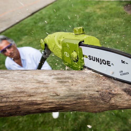 Sun Joe 6.5-amp 8-inch Electric Multi-Angle Pole Chain Saw cutting a tree limb.