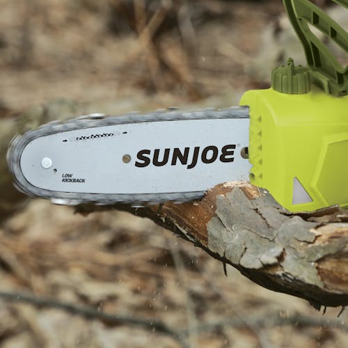 Close-up of the Sun Joe 6-amp 8-inch Electric Convertible Pole Chain Saw cutting though a branch.