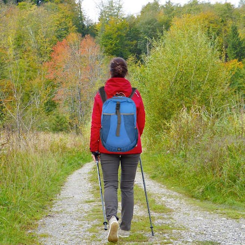 Person walking down a trail wearing the TrailGear 19-liter waterproof blue backpack.