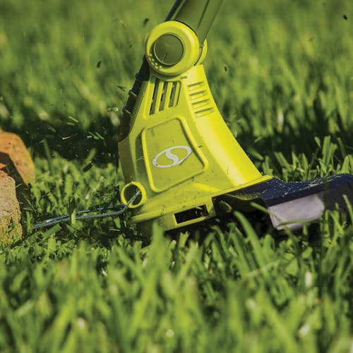 Close-up of the Sun Joe 4-amp 13-inch Electric String Grass Trimmer cutting grass.