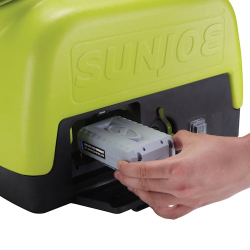 Person inserting a 2.0-Ah lithium-ion battery into the Sun Joe Cordless Go-Anywhere Portable Sink and Shower Spray Washer.