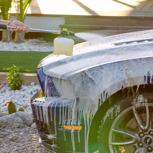 Sun Joe pressure washer detergent being used with a foam cannon to wash the hood of a car.