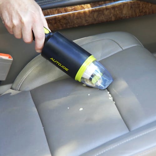 Auto Joe Cordless 8.4-Volt Handheld Vacuum Cleaner being used to clean the passenger seat.