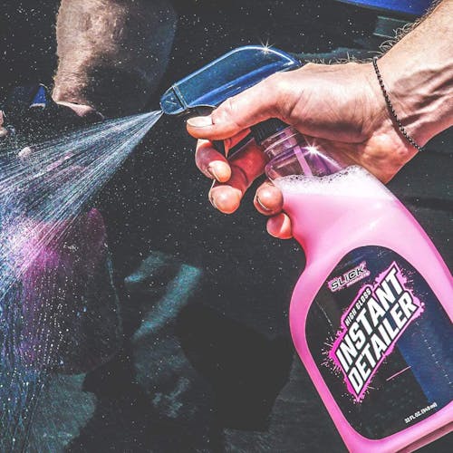 Person spraying the Slick Products 16 ounce High Gloss Finish Instant Detailer on a car.