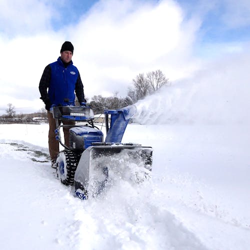 Snow Joe 100-volt 24-inch Cordless Dual-Stage Snow Blower being used to clear a pathway of snow.
