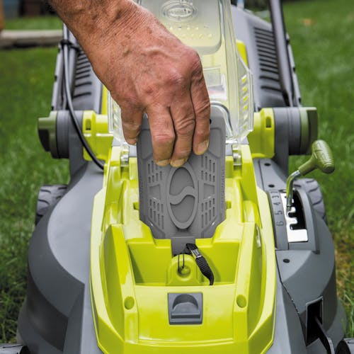 Close-up of a person inserting a 4.0-Ah battery into the Sun Joe 40-volt 16-inch Cordless Brushless Lawn Mower Kit.