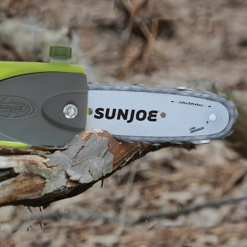 Sun Joe 40-volt 8-inch Cordless Multi-Angle Pole Chain Saw Kit cutting a branch.