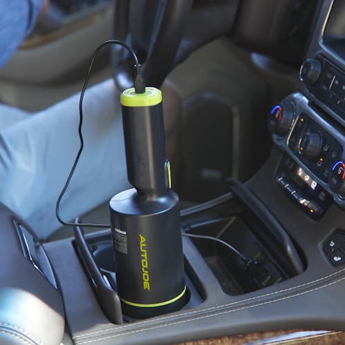 Auto Joe Cordless 8.4-Volt Handheld Vacuum Cleaner charging in the cup holder of a car.