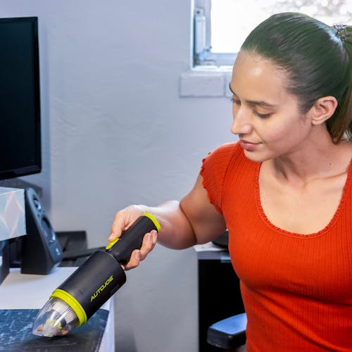 Auto Joe Cordless 8.4-Volt Handheld Vacuum Cleaner being used to clean a workspace.