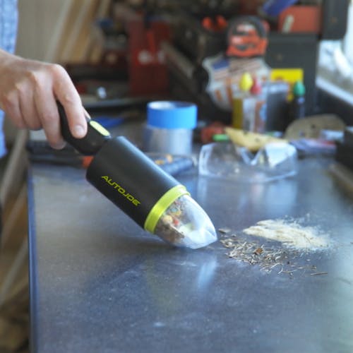 Auto Joe Cordless 8.4-Volt Handheld Vacuum Cleaner being used to clean a tabletop.