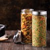 EatNeat Set of 2 72-ounce Large Glass Food Storage Containers with stainless steel lids filled with different foods on a counter.